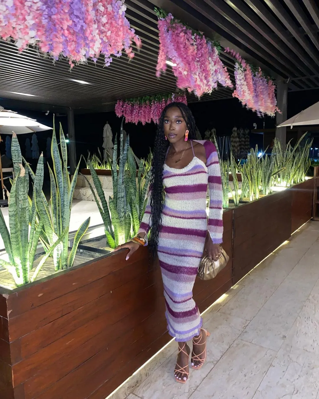 Ghanaian woman standing by greenery.